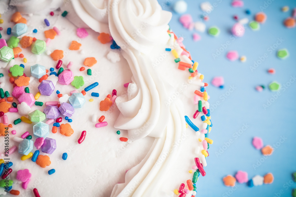 Up close view of a cake with colorful sprinkles on a light blue background Up close view of a cake with colorful sprinkles on a light blue background