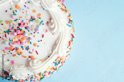 Top view of a cake with colorful sprinkles on a light blue background