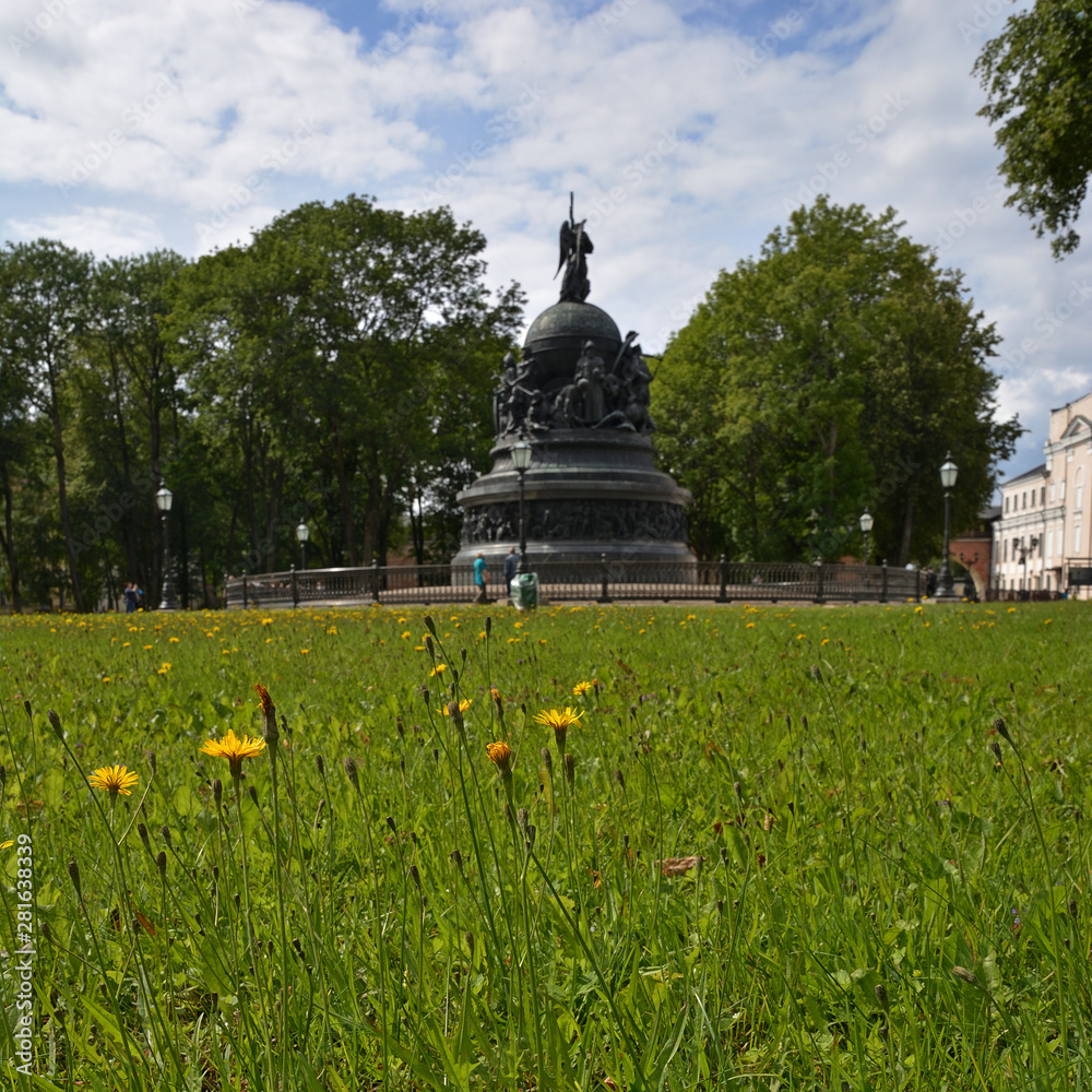 Veliky Novgorod. Summer green field with yellow flowers in the Kremlin and a monument to the millennium of Russia