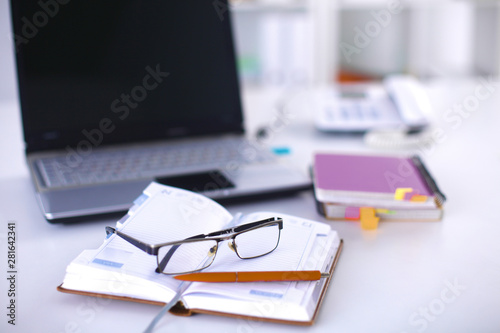 A note book, laptop, pen, graph paper document on the office de
