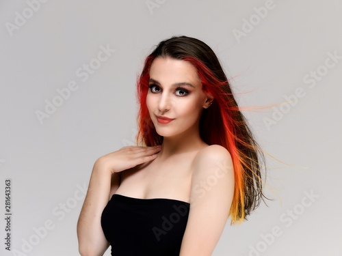 Studio portrait of a model with perfect makeup and colored hair on a white background. Beautiful female face of a pretty girl. Perfect makeup. Skin care. Fashionable cosmetics.