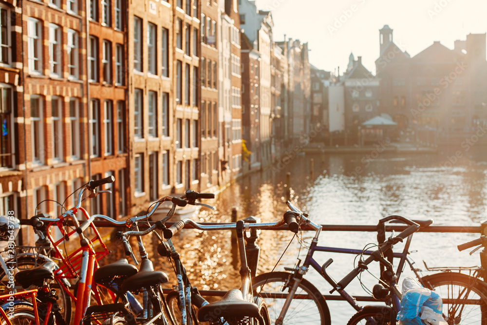 Bicycles standing by the canal in Amsterdam at sunset