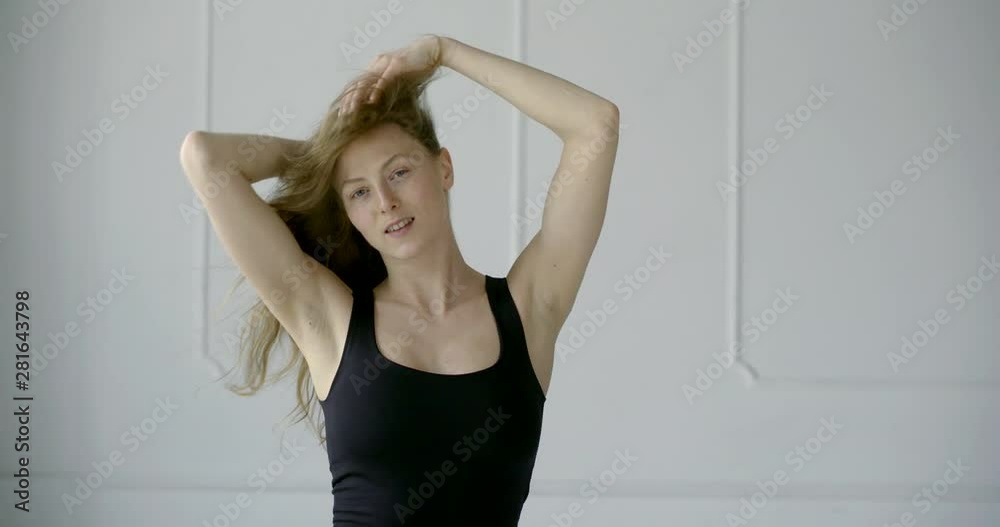 carefree young woman is playing with her beautiful light brown hair in studio room in daytime carefree young woman is playing with her beautiful light brown hair in studio room in daytime