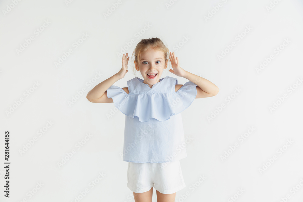 Stylish little smiling girl posing in casual clothes isolated on white studio background. Caucasian blonde female model. Human emotions, facial expression, childhood. Looks happy and amazed. Stylish little smiling girl posing in casual clothes isolated on white studio background. Caucasian blonde female model. Human emotions, facial expression, childhood. Looks happy and amazed.