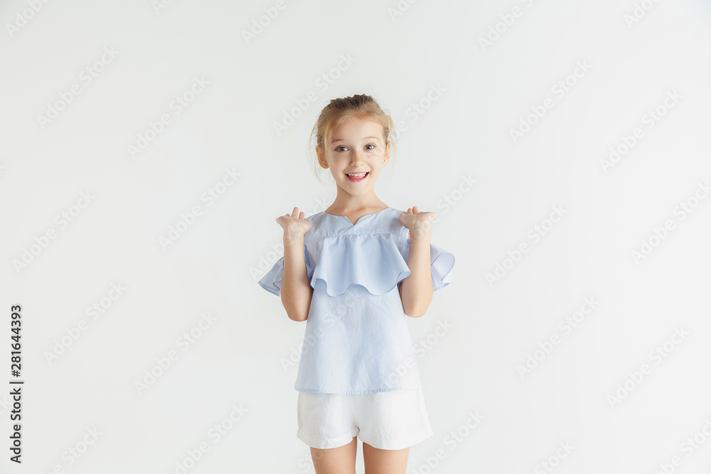 Stylish little smiling girl posing in casual clothes isolated on white studio background. Caucasian blonde female model. Human emotions, facial expression, childhood. Showing, inviting or greeting. Stylish little smiling girl posing in casual clothes isolated on white studio background. Caucasian blonde female model. Human emotions, facial expression, childhood. Showing, inviting or greeting.