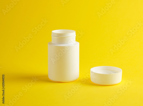 open white plastic jar for medicines stands on a yellow background
