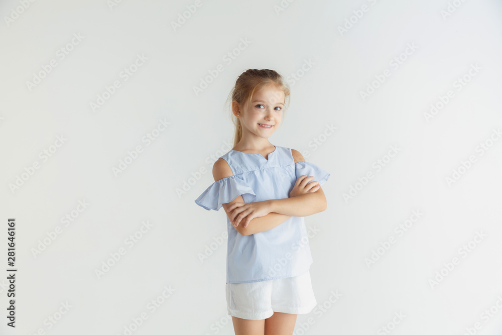Stylish little smiling girl posing in casual clothes isolated on white studio background. Caucasian blonde female model. Human emotions, facial expression, childhood, sales. Standing with hands Stylish little smiling girl posing in casual clothes isolated on white studio background. Caucasian blonde female model. Human emotions, facial expression, childhood, sales. Standing with hands