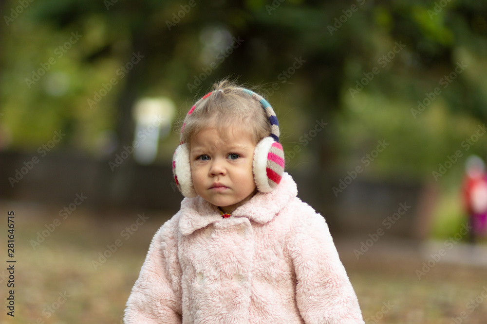 Beautiful and uncertain little girl in the autumn park looking at camera Beautiful and uncertain little girl in the autumn park looking at camera