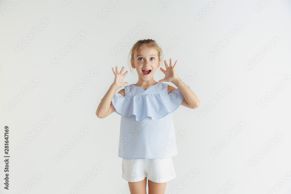 Stylish little smiling girl posing in casual clothes isolated on white studio background. Caucasian blonde female model. Human emotions, facial expression, childhood, sales. Shocked, astonished. Stylish little smiling girl posing in casual clothes isolated on white studio background. Caucasian blonde female model. Human emotions, facial expression, childhood, sales. Shocked, astonished.
