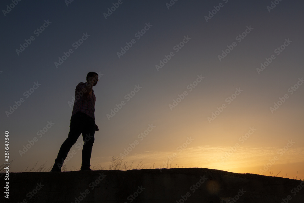 silhouette of man with cell phone at sunset