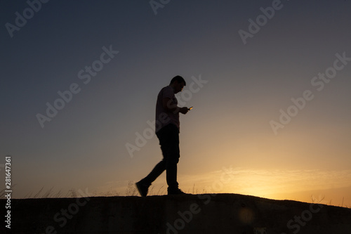 silhouette of man with cell phone at sunset © robcartorres