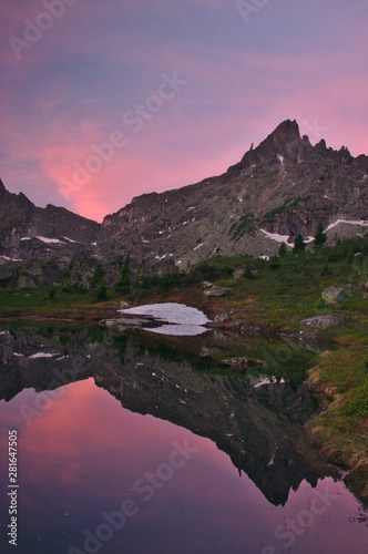 pink sky at sunset and reflection of mountains in mountain lake