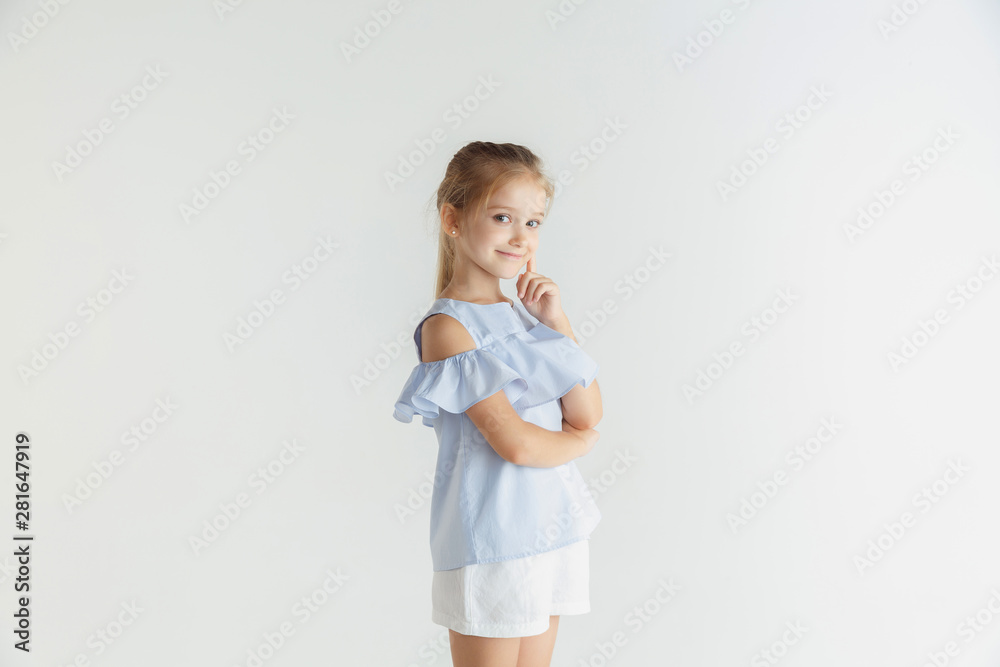 Stylish little smiling girl posing in casual clothes isolated on white studio background. Caucasian blonde female model. Human emotions, facial expression, childhood. Thoughtful. Thinking, choosing. Stylish little smiling girl posing in casual clothes isolated on white studio background. Caucasian blonde female model. Human emotions, facial expression, childhood. Thoughtful. Thinking, choosing.