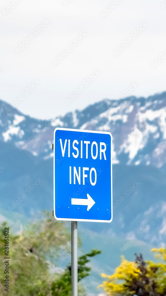 Vertical frame Close up of a Visitor Info sign with trees snowy mountain and sky background Vertical frame Close up of a Visitor Info sign with trees snowy mountain and sky background