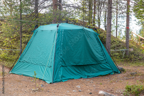 Tent for spending night and traveling green forest stands in Norway.