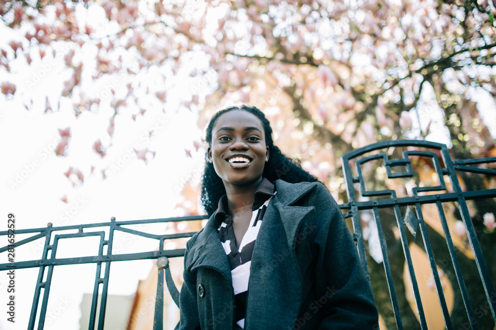 Young black woman with afro hairstyle smiling in urban park near ...