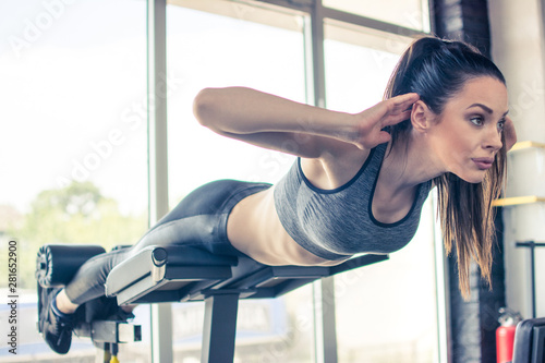 Beautiful fit woman doing back extension exercise on fitness machine in gym photo