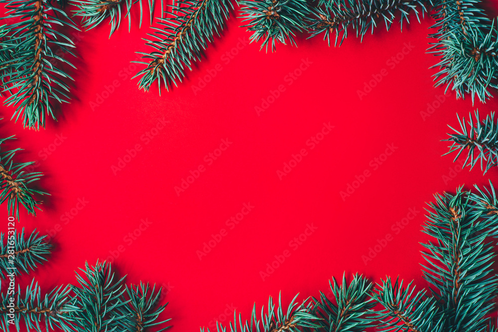 Fir branches on red background. Christmas wallpaper. Flat lay, copy space. Fir branches on red background. Christmas wallpaper. Flat lay, copy space.