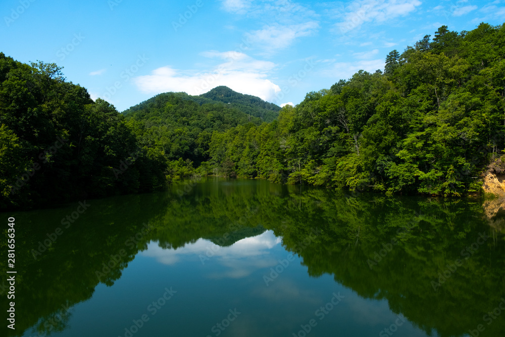 Blue sky and clouds reflected in the lake water in a cove