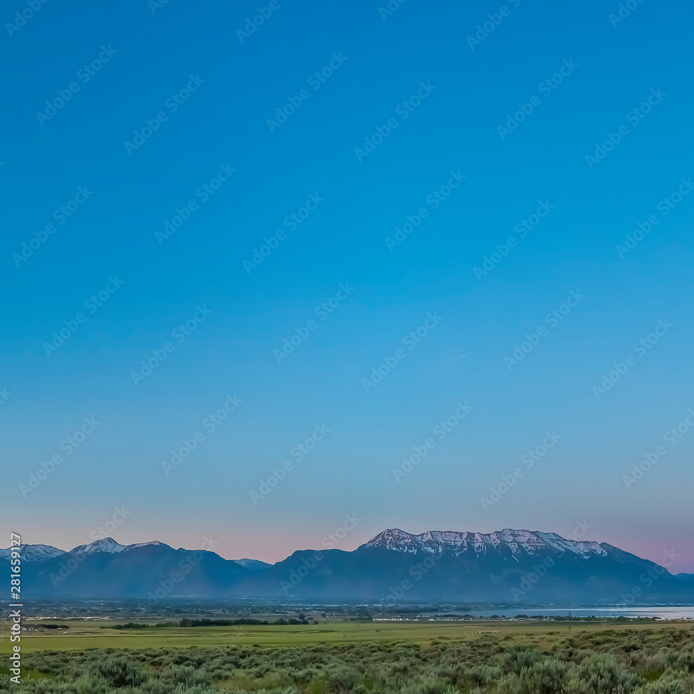 Obraz premium Square frame Scenic panoramic view of the valley lake and snow peaked mountain under blue sky