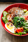 delicious and appetizing salad egg, tomato, spinach, cucumber, cheese, cilantro, lies on a red plate in a restaurant