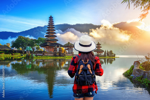 Woman traveler with backpack looking to pura ulun danu bratan temple in Bali, indonesia.