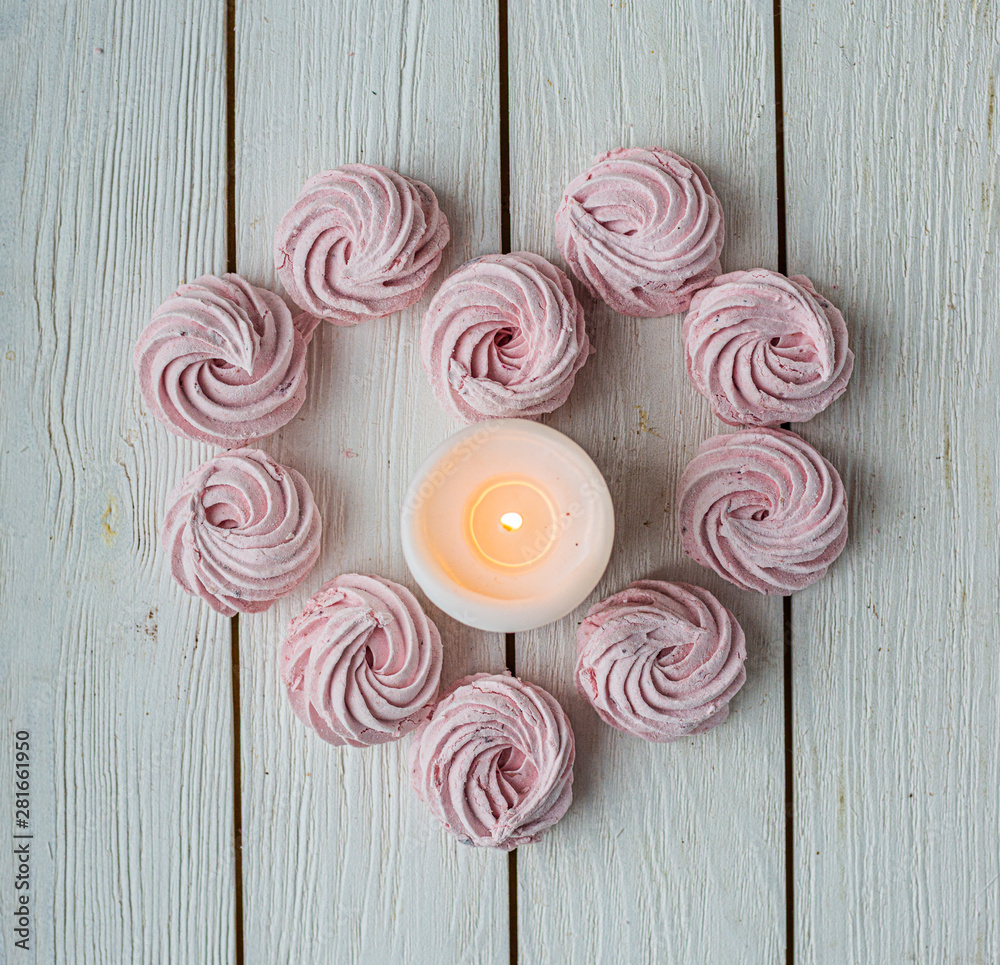 Zephyr lined in a heart shape with burning candles on a white background. Flat lay. Top view. Pink sweet homemade zephyr or marshmallow. Colorful meringues on white. top view dessert image. Zephyr lined in a heart shape with burning candles on a white background. Flat lay. Top view. Pink sweet homemade zephyr or marshmallow. Colorful meringues on white. top view dessert image.
