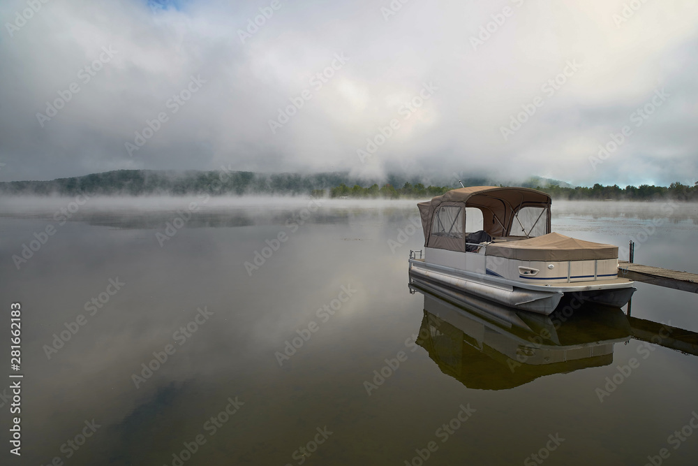 Morning landscape with autumn fog over the lake, a wooden pier and boats on the lake Massavippi, fog and sunlight.