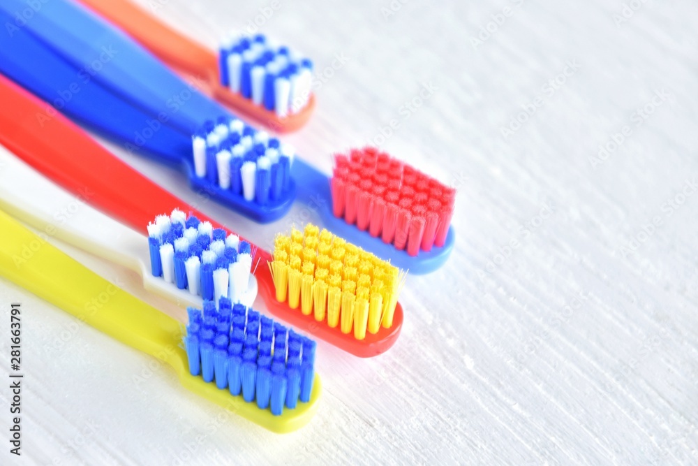 Colorful toothbrushes with selective focus on blurred neutral background. Dental tools for daily teeth protection. Multicolored plastic toothbrush with bright bristles with soft focus. Oral hygiene 