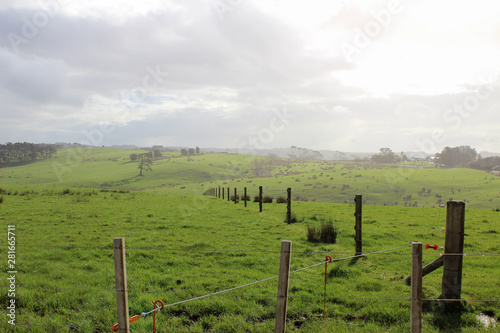 Majestic misty sunrise over rolling green hills with a fence 