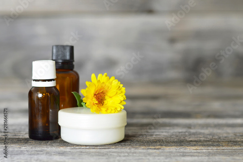 Calendula oil, cream and flower on wooden background