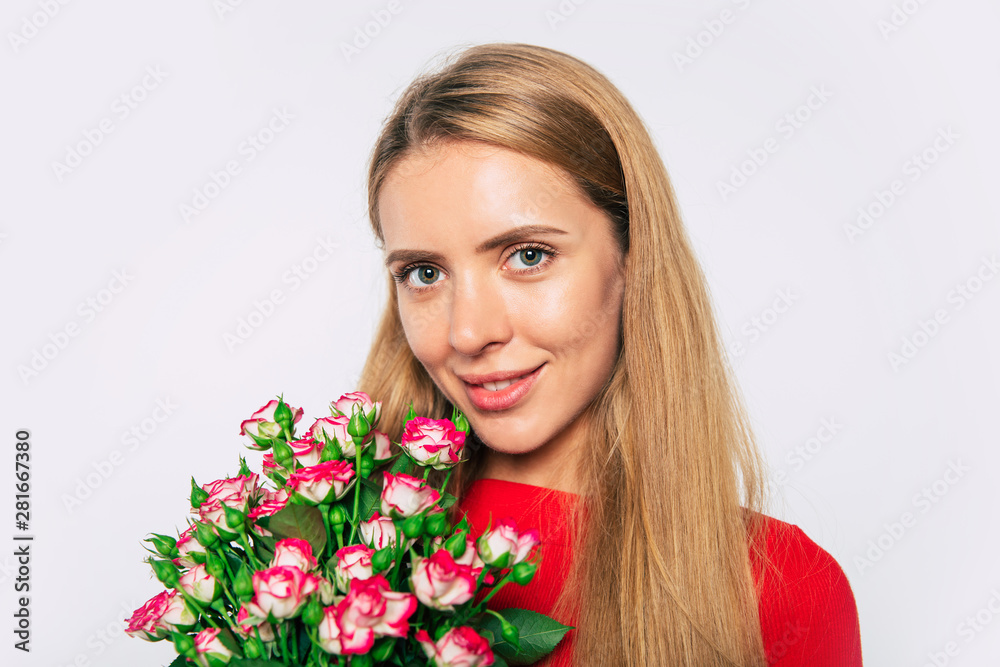 Close up shot of cute lovely blonde woman with large bouquet of roses while she looks on camera.