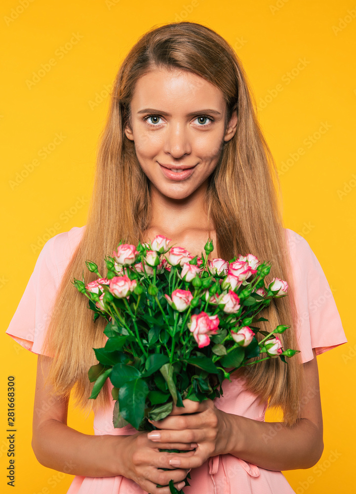 Close up portrait of tender attractive blonde woman with big bouquet of roses isolated on yellow wall background. Holidays and gifts concept. Women's day. St. Valentine's day