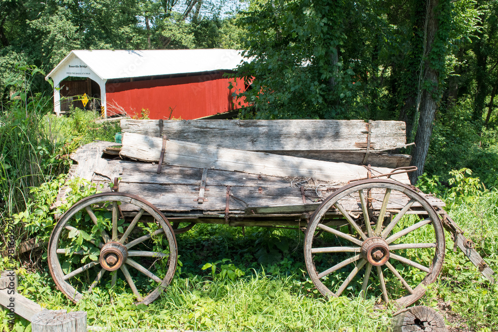 Dilapidated buckboard wagon with a covered bridge in the background in Parke County, Indiana