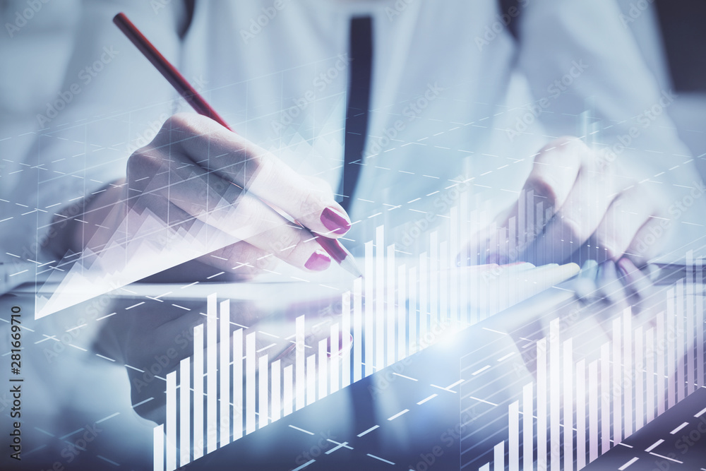 A woman hands writing information about stock market in notepad. Forex chart holograms in front. Concept of research. A woman hands writing information about stock market in notepad. Forex chart holograms in front. Concept of research.
