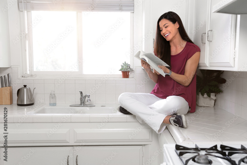 Casual calm female leisure time reading a book at home in the morning sunlight, kitchen counter Casual calm female leisure time reading a book at home in the morning sunlight, kitchen counter