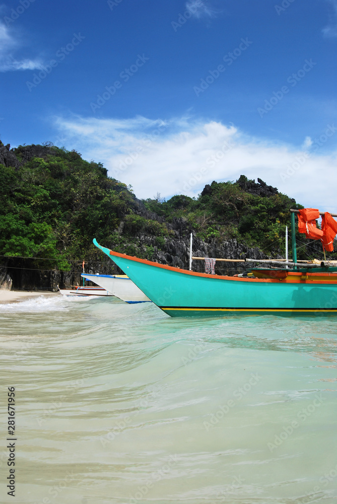 Natural landscape: tropical sand beach with forest, crystal clear sea and a boat on the foreground.