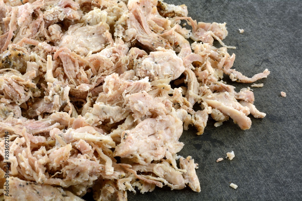 Cold cooked pulled pork meat on black cutting board ready to be reheated