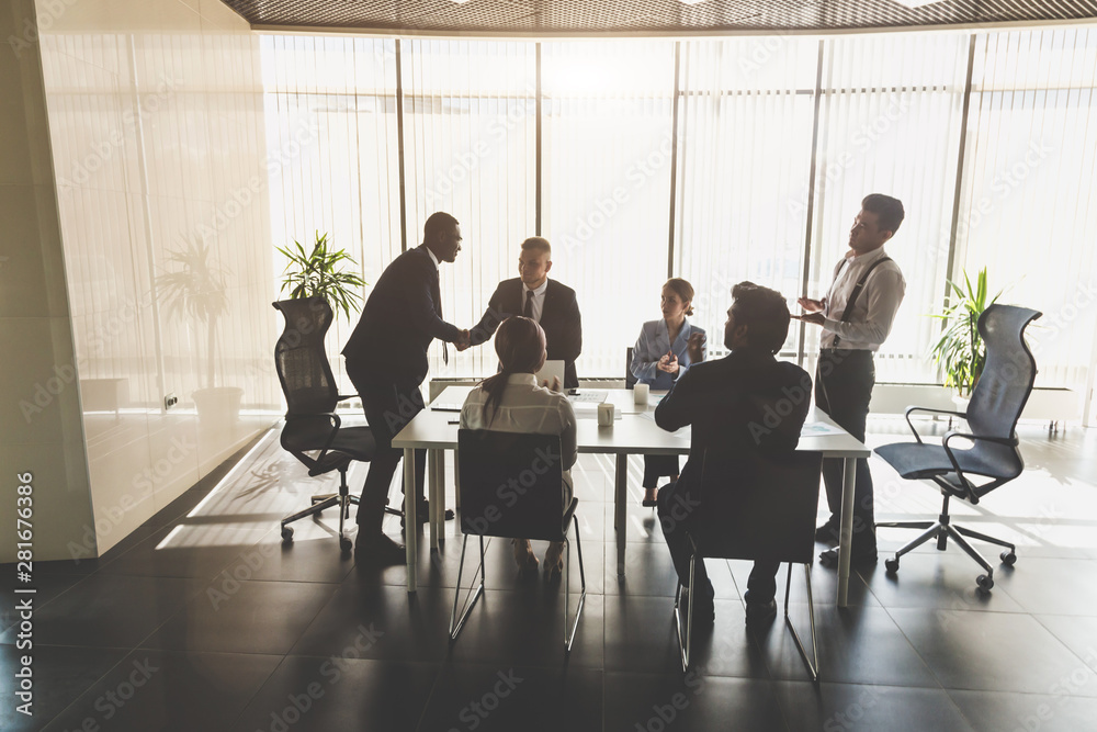 Silhouettes of people sitting at the table. A team of young businessmen working and communicating together in an office. Corporate businessteam and manager in a meeting Silhouettes of people sitting at the table. A team of young businessmen working and communicating together in an office. Corporate businessteam and manager in a meeting