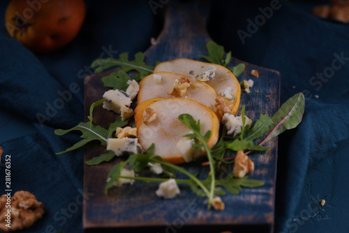 Sliced pears, nuts and cheese on a wooden board