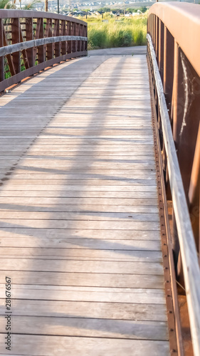 Vertical Close up of a bridge with wooden deck and brown lattice guardrail on a sunny day