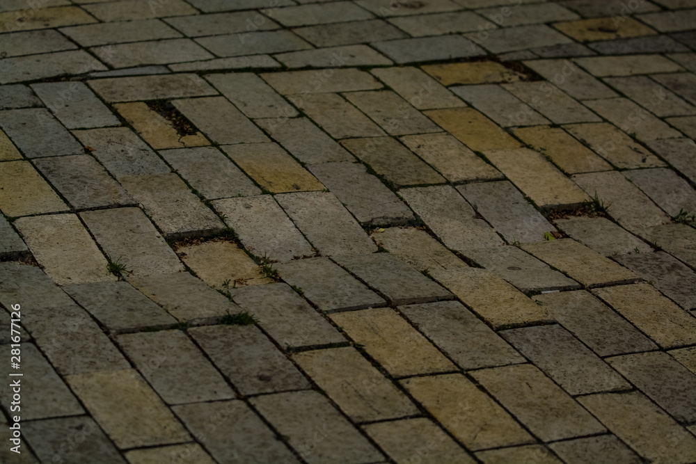 Background or texture from a broken and equal tile with patches of light and drops. Stone blocks on the sidewalk.