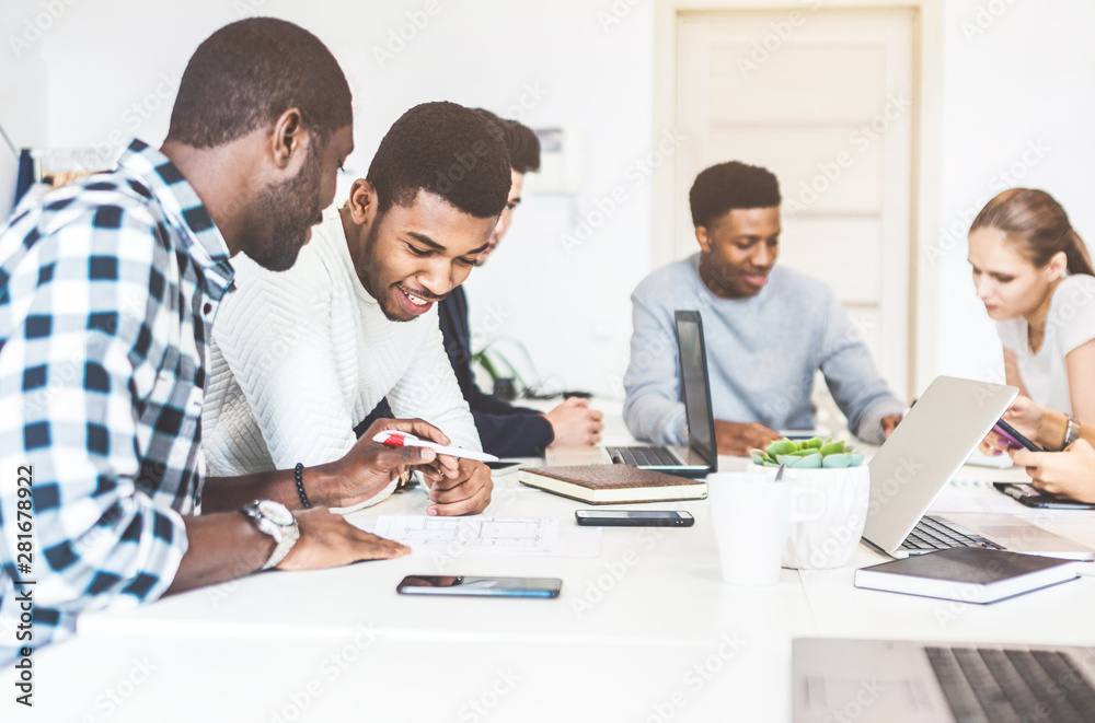 A team of young office workers, businessmen with laptop working at the table, communicating together in an office. Corporate businessteam and manager in a meeting. coworking. A team of young office workers, businessmen with laptop working at the table, communicating together in an office. Corporate businessteam and manager in a meeting. coworking.