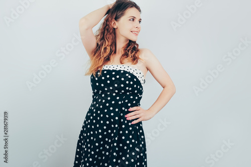 Portrait of beautiful young woman with ombre wavy hair. Pretty girl in retro dress dreamily looking aside posing on grey background.