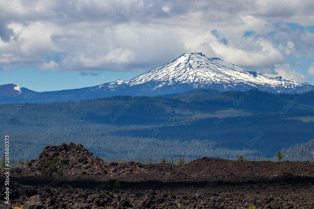 Snow capped mountain with lava rock in the foreground