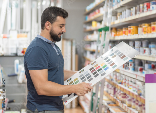 Man in drugstore selecting paint color for his work