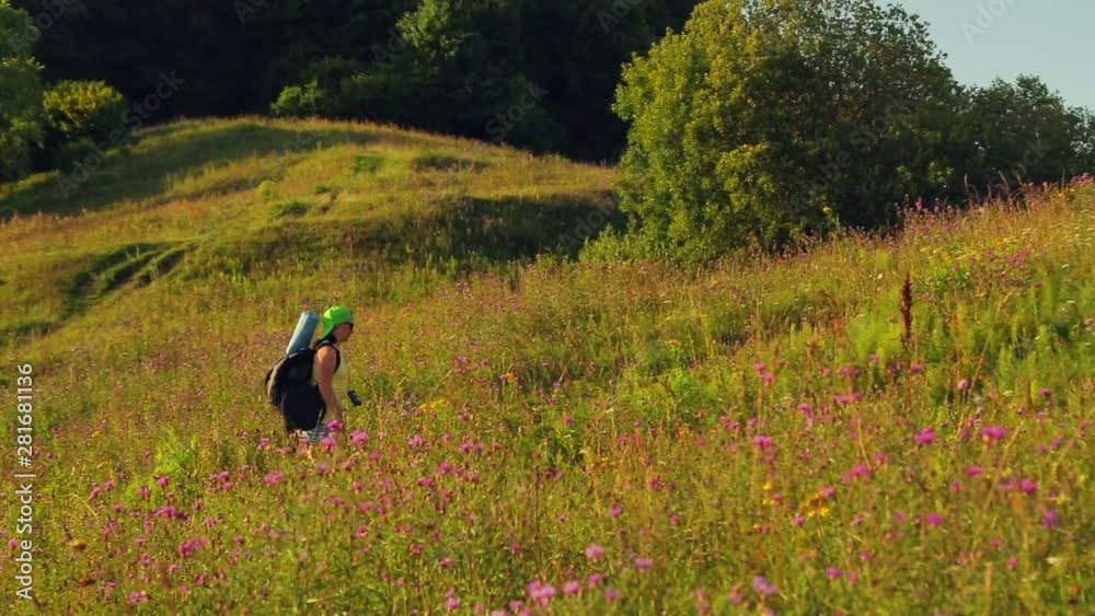 Woman hiker climbs uphill with a backpack over her shoulders and binoculars