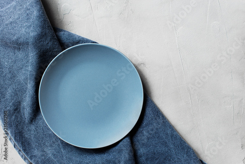 Obraz na plátne Light grey table with empty blue plate and denim napkin