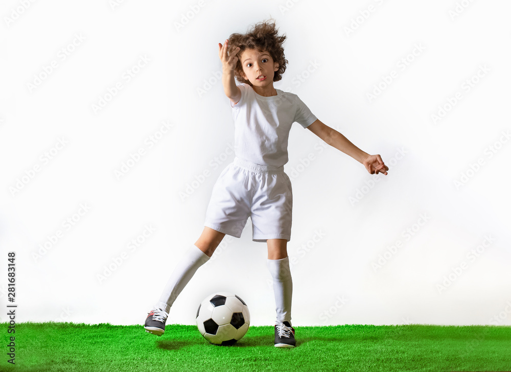 Boy with soccer ball on the green grass.Excited little toddler boy playing football on soccer field against light background. Active childhood and sports passion concept. Save space