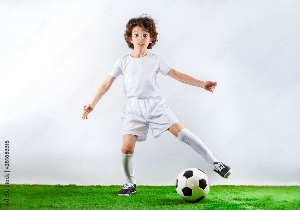 Boy with soccer ball on the green grass.Excited little toddler boy playing football on soccer field against light background. Active childhood and sports passion concept. Save space